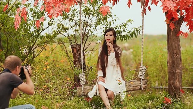 The photographer takes photos of asian girl in the autumn garden.