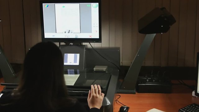 Woman putting a sheet of old manuscript into a high resolution scanning device