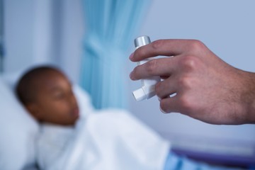 Hand of nurse holding asthma pump in ward