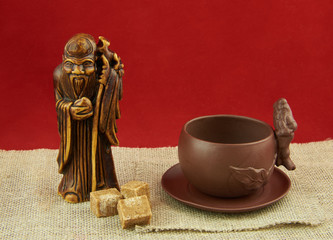 Still life with a statuette of the god of tea, a cup and lumps o