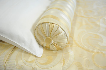 Decorative pillow-cushion of golden fabric on the bed. Closeup