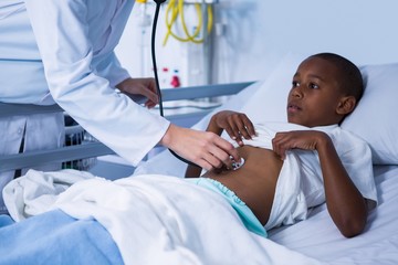 Doctor examining patient with stethoscope in ward