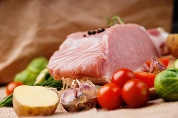 Raw pork and vegetables on a canvas background