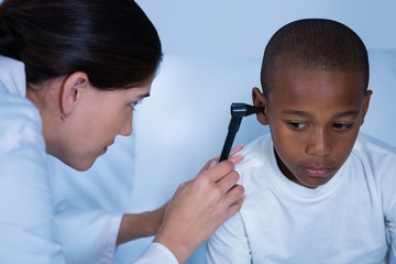 Female doctor examining patient ear with otoscope
