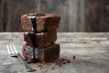 Chocolate brownie with chocolate syrup on wooden background
