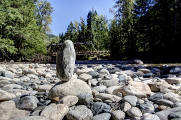 Rock balanced on another rock along a river bank