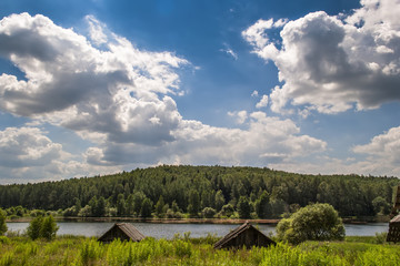 Fototapeta na wymiar Forest on the banks of the pond and beautiful clouds 