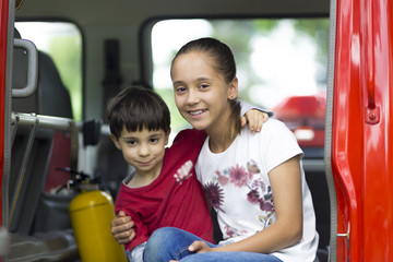 Happy Girl and Boy in Firefighter Car