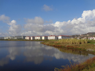 Fototapeta na wymiar Apartment buildings and hotels on the shore of the lake, reflection clouds in water