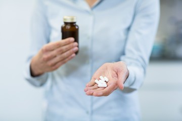 Pharmacist holding a medicine bottle and pills in pharmacy