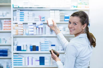 Fotobehang Apotheker die geneeskunde in plank bij apotheek controleert © WavebreakMediaMicro
