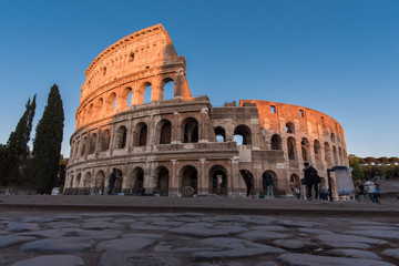 Fototapeta premium Koloseum rzymskie o zachodzie słońca z górą oświetloną przez wieczorne słońce