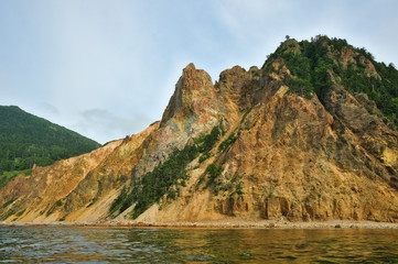 Colorful rocks. Red Rock Cape, Okhotsk Sea coast, Kunashir Island, Kuril archipelago, Russia. - 130651559