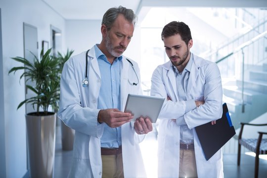 Doctors having discussion over digital tablet in corridor