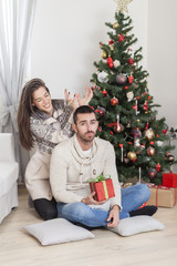 Obraz na płótnie Canvas Happy Young couple having fun on Christmas at home