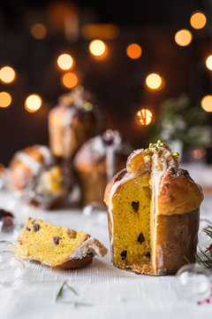 fetta di panettone con marron glac&egrave; e cioccolato. Sfondo con luci di natale e altri panettoni sfocati 