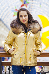 Beautiful brunette woman in golden fur coat