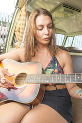 Young woman plays guitar in Combi Van