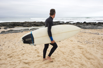 Walking along the Beach with Surfboard