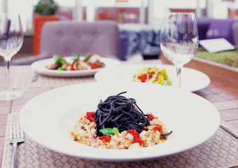 Black squid ink pasta with seafood and other dishes, toned