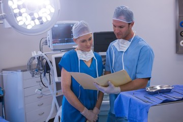 Male and female nurse having discussion over file 