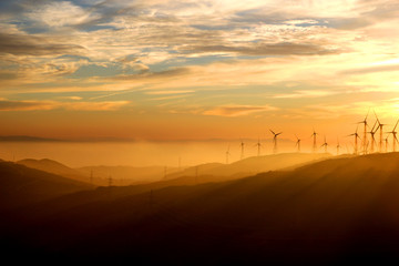 Silhouettes of wind turbines on the hills of Andalusia at sunset
