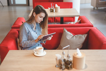 Candid image of young woman using tablet computer in a cafe
