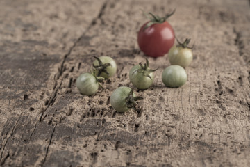Ripe and unripe tomatoes on wooden table