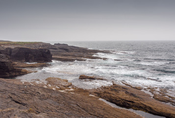 Fototapeta na wymiar Waves crashing on large rocks at Hook Head, Wexford, Republic of Ireland.