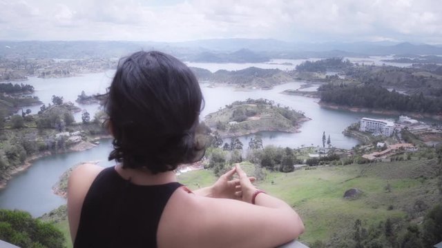 Hispanic woman contemplating the panoramic view the Guatape Islands from the rock called the Peñol. 4k