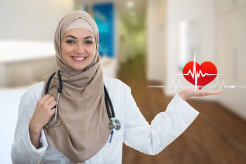Closeup portrait of friendly, smiling confident Muslim female doctor holding EKG sign