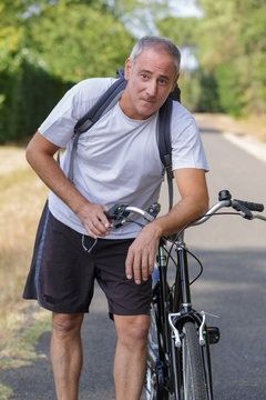 mature man cyclist next to a bicycle