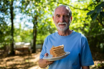 Fototapeta premium Senior man holding slice bread in a plate