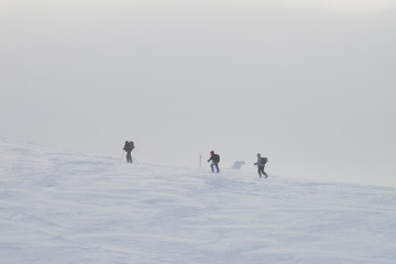 Group of people hiking in winter mountains during a snow storm