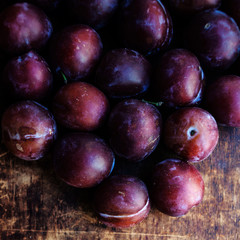 Obraz premium Fresh plums on a dark wood background. Top view image. .Ripe Plu