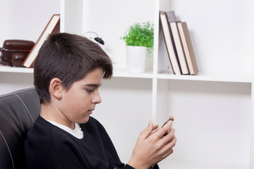 child at home on the sofa with the phone mobile playing, talking or chatting