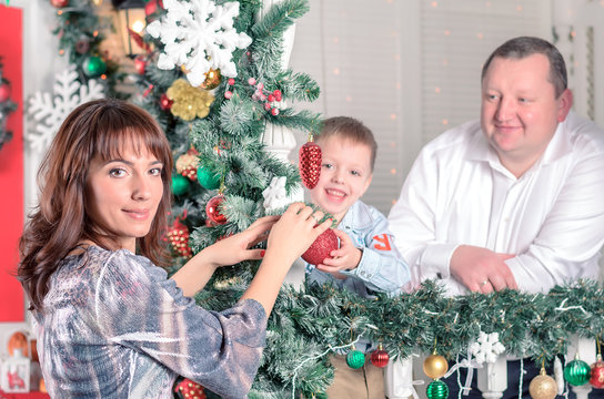 Family decorating a Christmas tree with boubles in the living-room
