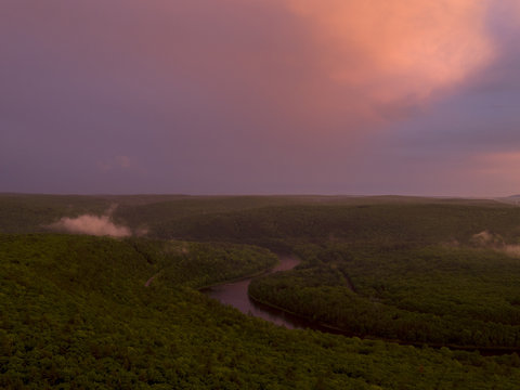 View of river running through dense trees at sunset