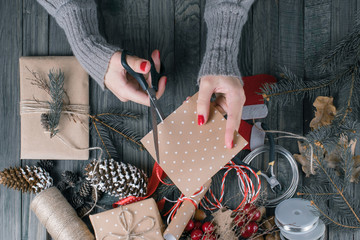 Top view of woman's hands cutting gift paper for Christmas present