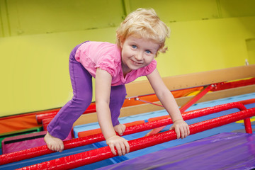 Portrait of white blonde Caucasian happy smiling baby girl child doing exercises in gym enjoying sport class