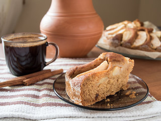 Vegetarian apple cake with a cap of coffee on the wooden table