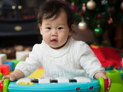 Asian baby girl playing piano toy