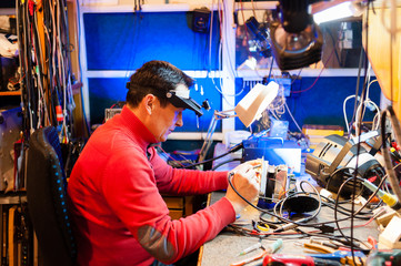Electrician with soldering iron repairs device for stage lighting