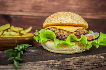 Great Hamburger and french fries on a wooden table in rustic style. Close-up