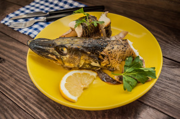 Pike baked with vegetables on the table. Wooden rustic background. Close-up