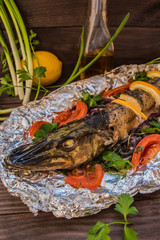 Pike baked with vegetables on the table. Wooden rustic background. Close-up