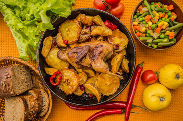 Quail baked in a pan with potatoes and apples. On the golden background. Top view. Close-up
