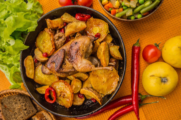 Quail baked in a pan with potatoes and apples. On the golden background. Top view. Close-up