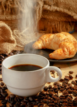 Hot coffee cup and breakfast baked croissants on wooden background