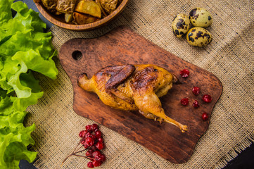 Roasted quail with greens on a wooden Boards. Top view. Close-up